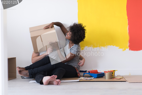 Image of young multiethnic couple playing with cardboard boxes