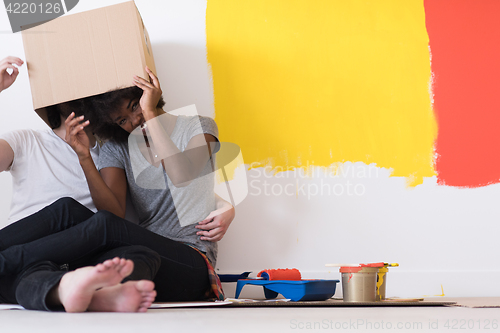 Image of young multiethnic couple playing with cardboard boxes