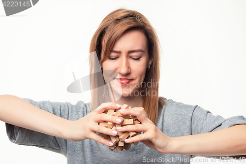 Image of Attractive 24 year old business woman looking confused with wooden puzzle.