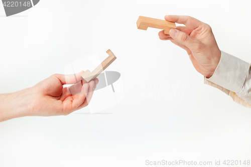 Image of The toy wooden puzzle in hands solated on white background