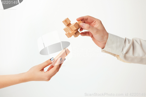 Image of The toy wooden puzzle in hands isolated on white background