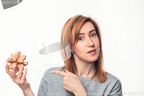 Image of Attractive 24 year old business woman looking confused with wooden puzzle.