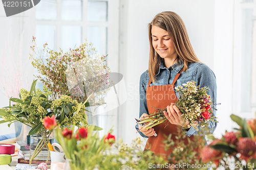 Image of Florist at work: the young girl making fashion modern bouquet of different flowers