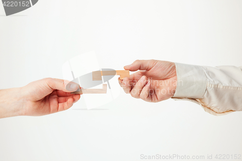 Image of The toy wooden puzzle in hands solated on white background