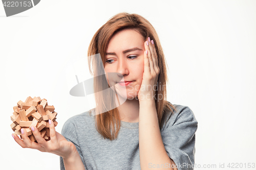 Image of Attractive 24 year old business woman looking confused with wooden puzzle.