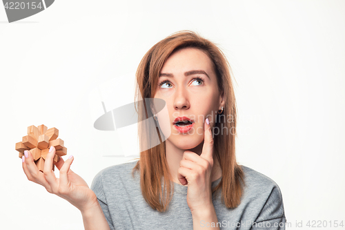 Image of Attractive 24 year old business woman looking confused with wooden puzzle.