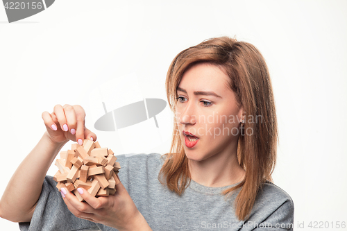 Image of Attractive 24 year old business woman looking confused with wooden puzzle.