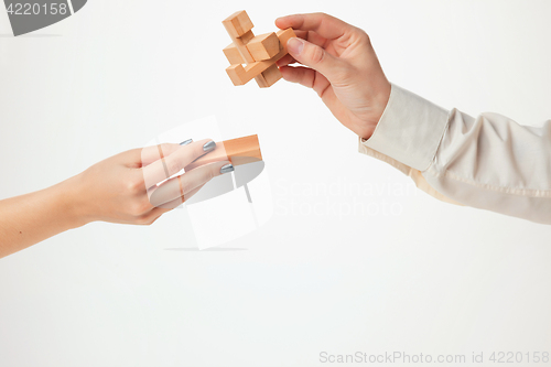 Image of The toy wooden puzzle in hands isolated on white background