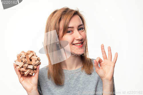 Image of Attractive 24 year old business woman looking confused with wooden puzzle.