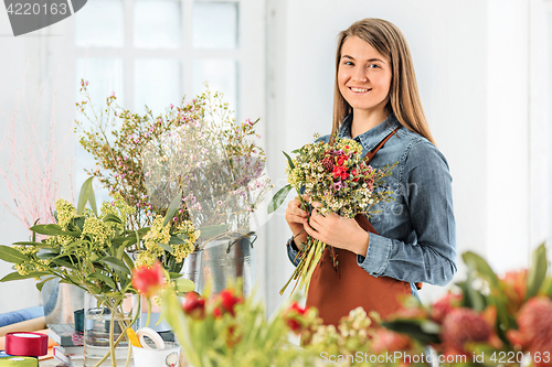 Image of Florist at work: the young girl making fashion modern bouquet of different flowers