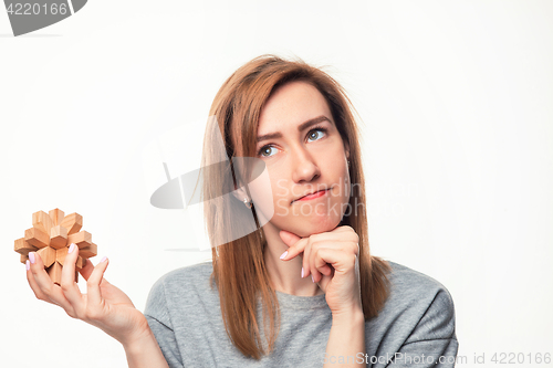 Image of Attractive 24 year old business woman looking confused with wooden puzzle.