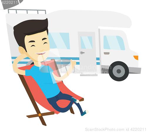 Image of Man sitting in chair in front of camper van.