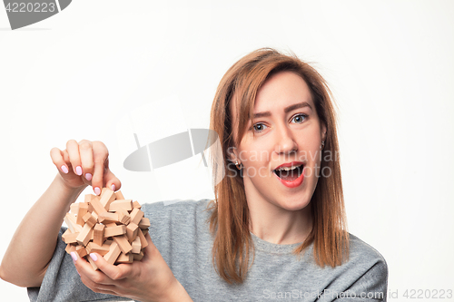 Image of Attractive 24 year old business woman looking confused with wooden puzzle.