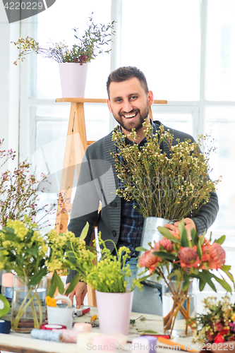 Image of Florist at work: the young MAN making fashion modern bouquet of different flowers