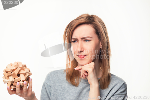 Image of Attractive 24 year old business woman looking confused with wooden puzzle.