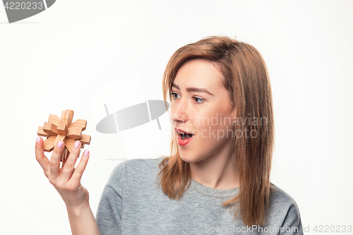 Image of Attractive 24 year old business woman looking confused with wooden puzzle.