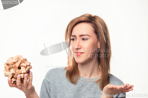 Image of Attractive 24 year old business woman looking confused with wooden puzzle.