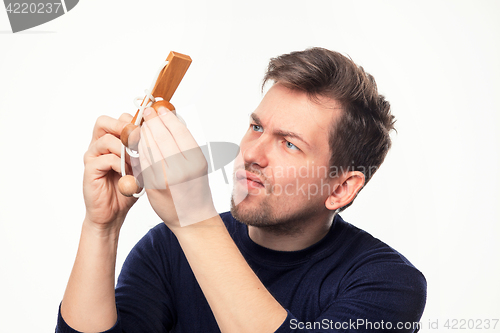 Image of Attractive 25 year old business man looking confused at wooden puzzle.