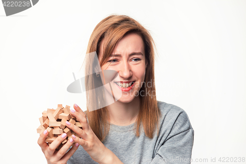 Image of Attractive 24 year old business woman looking confused with wooden puzzle.