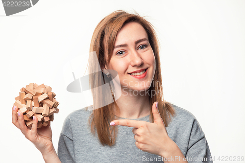 Image of Attractive 24 year old business woman looking confused with wooden puzzle.