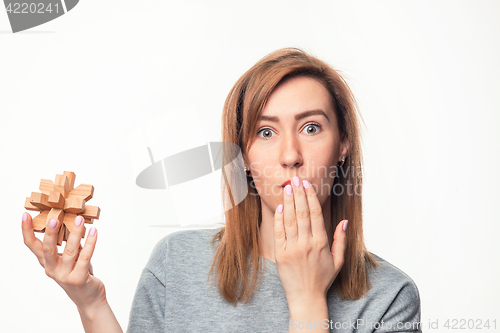 Image of Attractive 24 year old business woman looking confused with wooden puzzle.