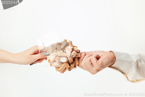 Image of The toy wooden puzzle in hands isolated on white background