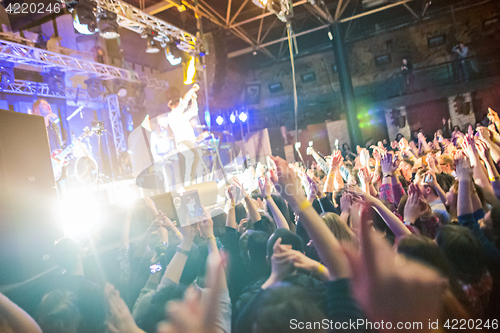 Image of The silhouettes of concert crowd in front of bright stage lights