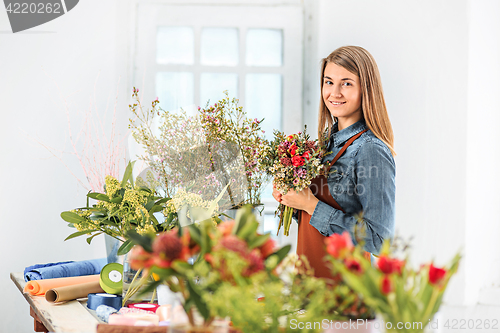 Image of Florist at work: the young girl making fashion modern bouquet of different flowers