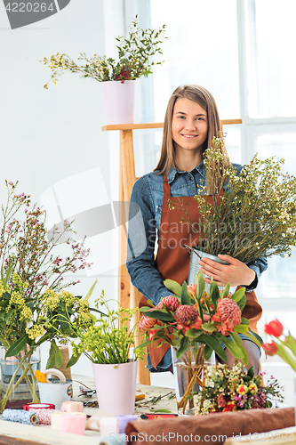 Image of Florist at work: the young girl making fashion modern bouquet of different flowers