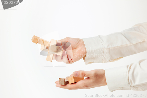 Image of The toy wooden puzzle in hands solated on white background