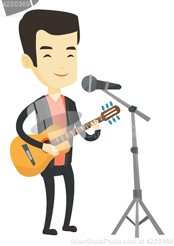 Image of Man singing in microphone and playing guitar.