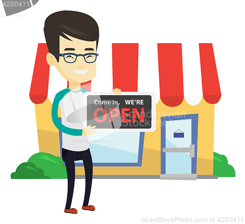 Image of Asian shop owner holding open signboard.