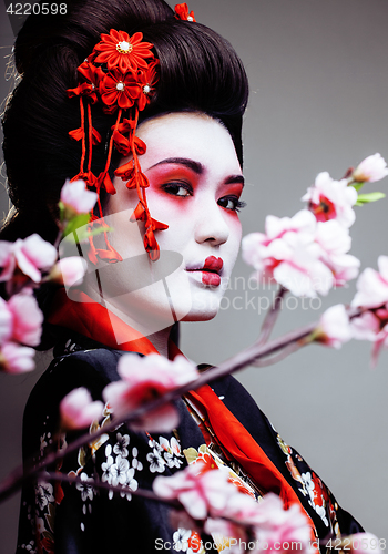 Image of young pretty geisha in kimono with sakura and decoration