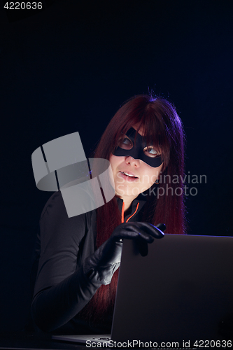 Image of Thief in mask with laptop