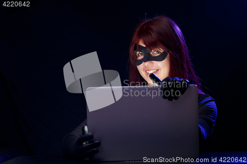 Image of Thief in mask holds laptop