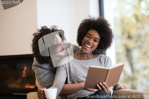 Image of multiethnic couple hugging in front of fireplace