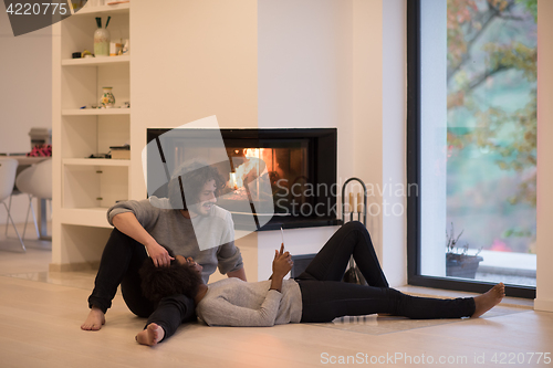 Image of multiethnic couple using tablet computer on the floor