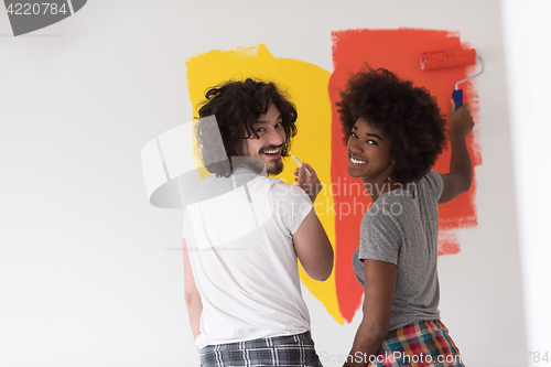 Image of multiethnic couple painting interior wall