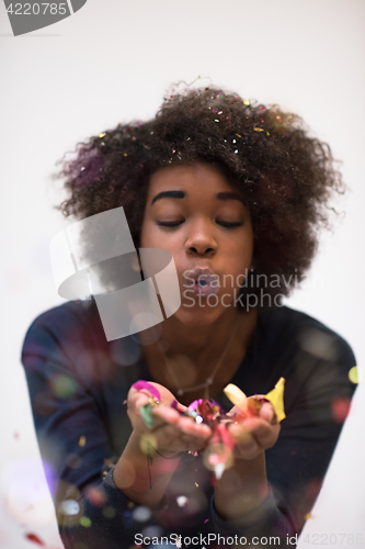 Image of African American woman blowing confetti in the air