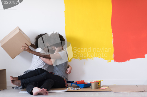 Image of young multiethnic couple playing with cardboard boxes