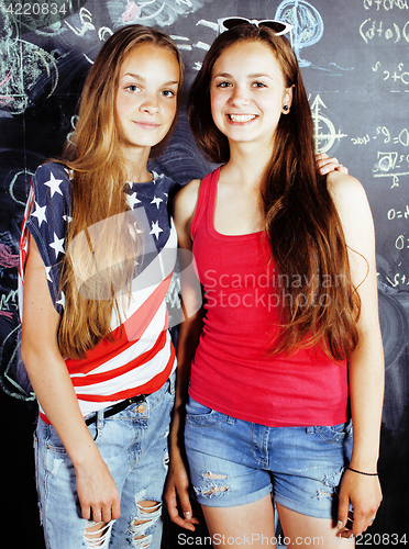 Image of back to school after summer vacations, two teen real girls in classroom with blackboard painted together, lifestyle people concept