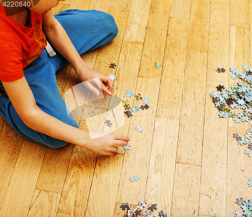 Image of little kid playing with puzzles on wooden floor together with parent, lifestyle people concept, loving hands to each other 