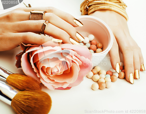 Image of woman hands with golden manicure and many rings holding brushes, makeup artist stuff stylish, pure beauty