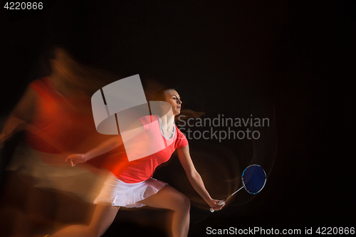 Image of Young woman playing badminton over black background