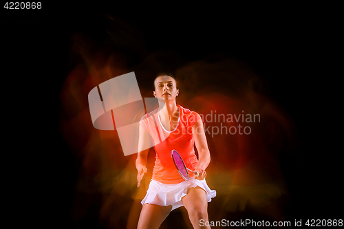 Image of Young woman playing badminton over black background