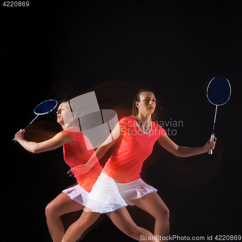 Image of Young woman playing badminton over black background