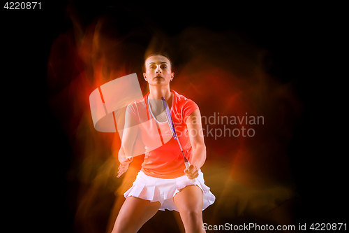 Image of Young woman playing badminton over black background