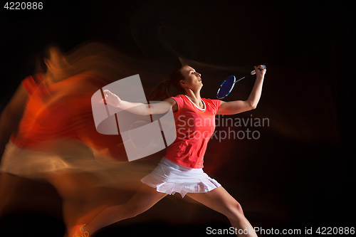 Image of Young woman playing badminton over black background