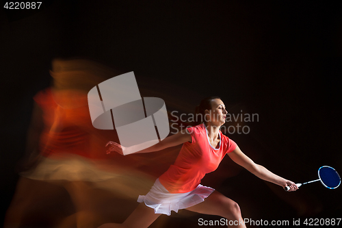 Image of Young woman playing badminton over black background