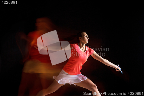 Image of Young woman playing badminton over black background